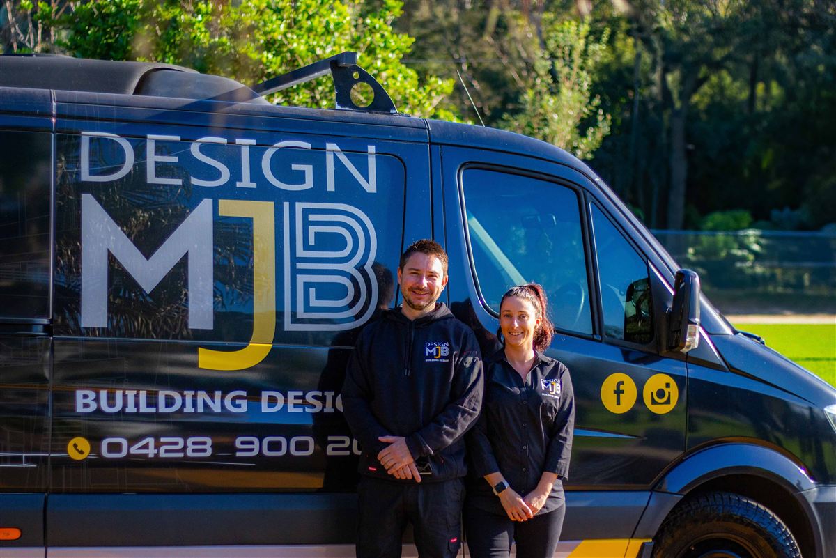 Michael Baczkowski and Bianca Baldwin standing beside the Design MJB Building Design van
