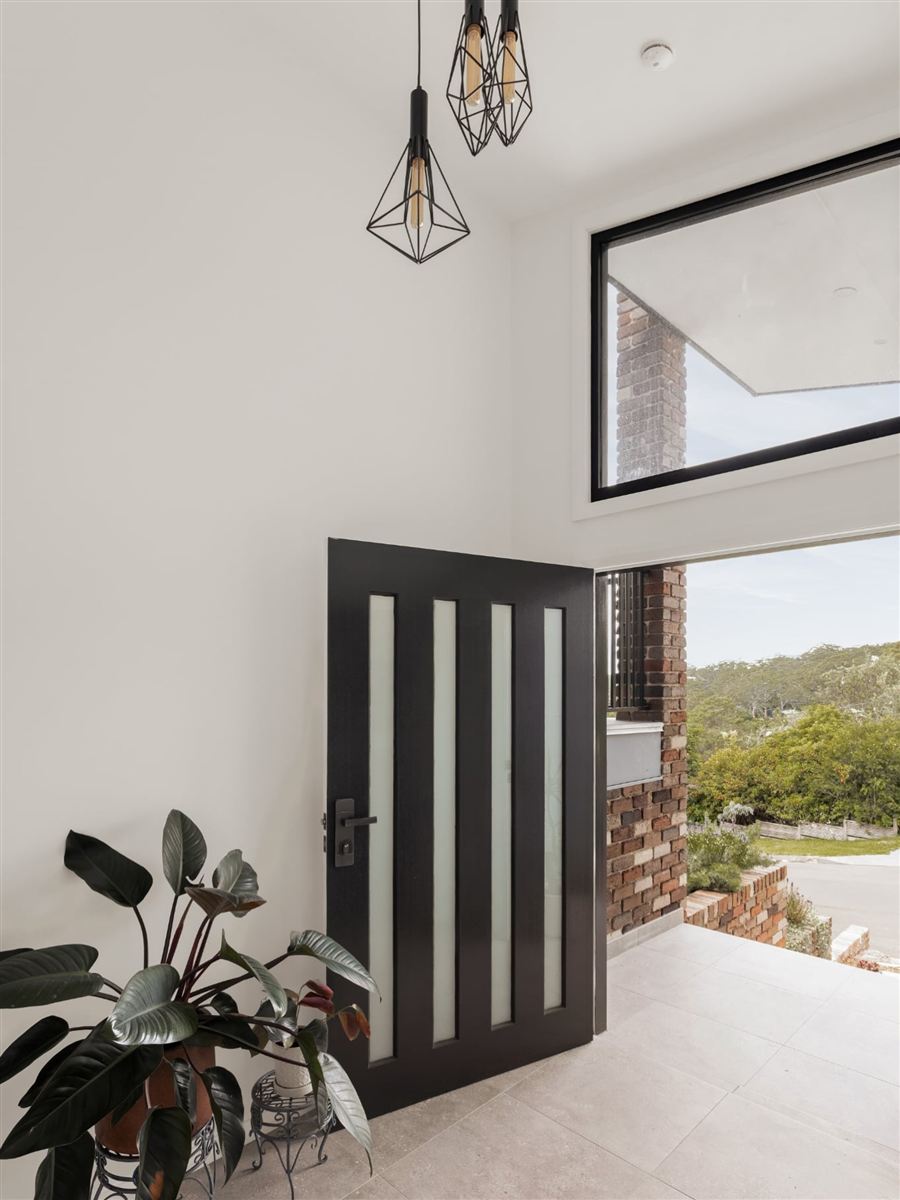 Renovated home entry with black feature door and pendant lighting