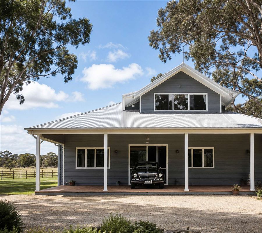 Grey weatherboard homestead design with wraparound verandah and dormer window